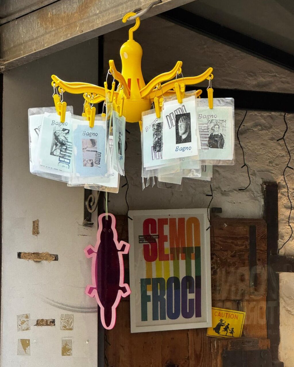 The MetaBagno prints hanging on a clothes airer at the entrance of Libreria L’Ornitorinco, Florence