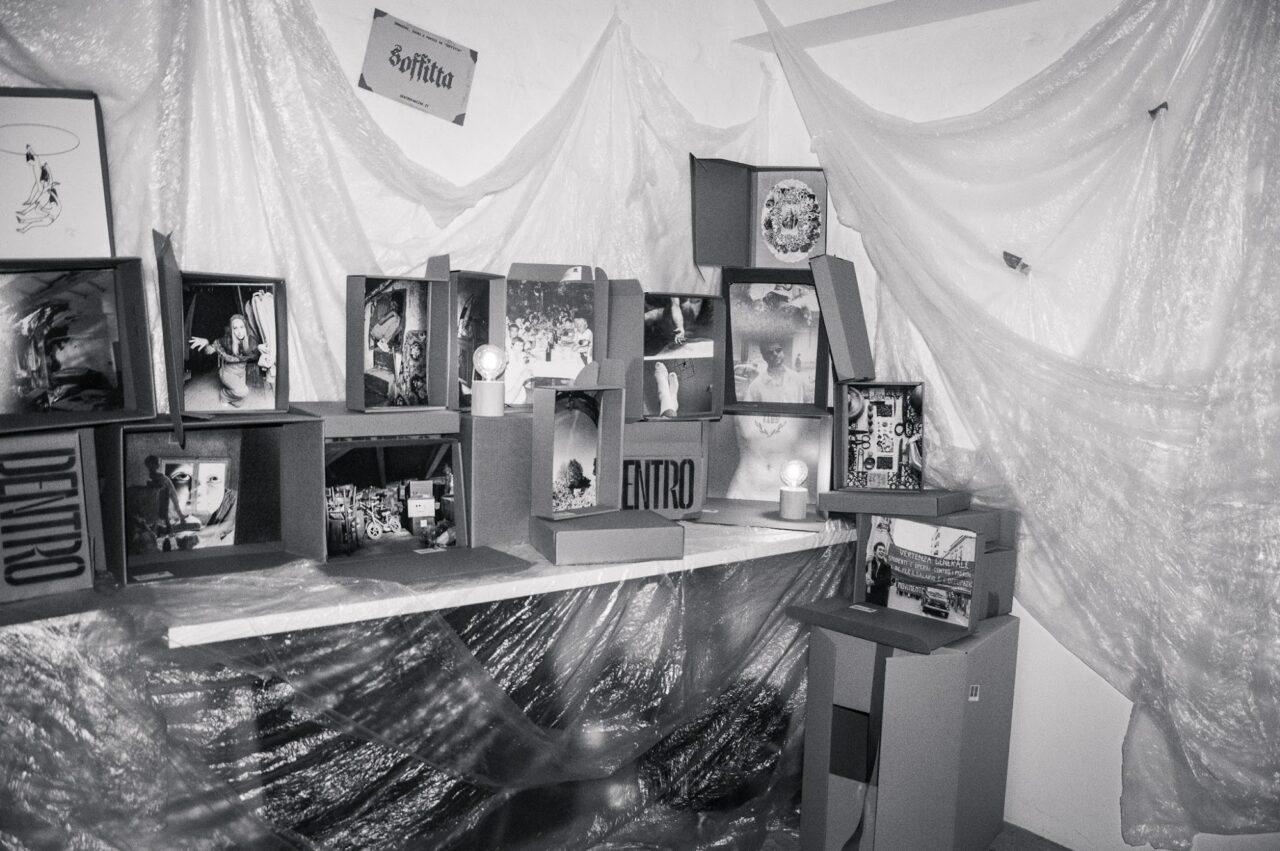 The DENTRO Attic exhibition set-up at Libreria Igor, Bologna: cardboard boxes, light bulbs and artworks